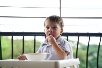 Menino comendo em um assento de bebê na varanda — Fotografia de Stock