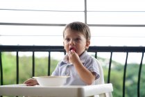 Baby boy eating in a baby seat on the balcony — Stock Photo