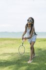 Молодая маленькая милая азиатская девочка с бадминтонной ракетой в парке — стоковое фото