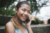 Junge asiatische sportliche Frau benutzt Smartphone im Park — Stockfoto
