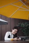 Красива китайська довге волосся жінка використовує смартфон у кафе — стокове фото