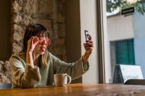 Young casual asian girl taking selfie in cafe — Stock Photo