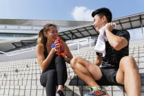 Giovane coppia sportiva rilassante e acqua potabile sulle scale — Foto stock