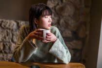 Молода випадкова азіатська дівчина п'є каву в кафе — стокове фото
