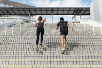 Giovane coppia sportiva correndo insieme sulle scale, vista posteriore — Foto stock