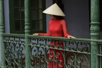 Mulher vietnamita usando chapéu cônico em pé em uma varanda em Hoi An em seu Ao Dai — Fotografia de Stock