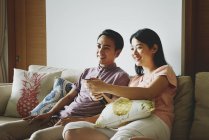 Adult asian couple together watching tv at home — Stock Photo