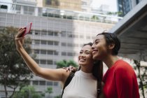 Jovem asiático feminino amigos juntos tomando selfie no cidade rua — Fotografia de Stock