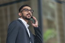 Homem de negócios indiano bonito usando smartphone ao ar livre — Fotografia de Stock