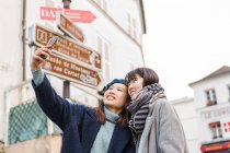 Young casual asian girls taking selfie on smartphone in city — Stock Photo
