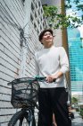 Jóvenes empresarios asiáticos en la ciudad con bicicletas - foto de stock