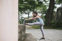 Молода азіатська спортивна жінка робить розтягування в парку — стокове фото