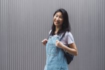 Молодий азіатський студент коледжу позує на сіру стіну — стокове фото