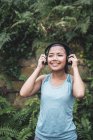 Giovane asiatica donna sportiva che indossa le cuffie nel parco — Foto stock