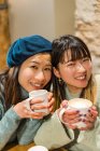 Young casual asian girls drinking coffee in cafe — Stock Photo
