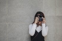 Bastante chino largo cabello mujer tomando foto con cámara - foto de stock