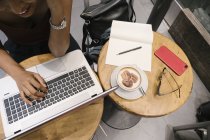 Image recadrée de jeune femme asiatique attrayante en utilisant un ordinateur portable dans un café — Photo de stock