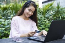 Beautiful Malay lady making an online purchase with her credit card — Stock Photo