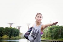 Young sporty asian woman making stretching at park — Stock Photo