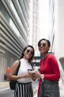 Young asian female friends together with coffee on city street — Stock Photo