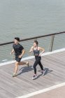 Young sporty couple running on pier — Stock Photo