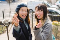 Young casual asian girls showing heart gesture — Stock Photo