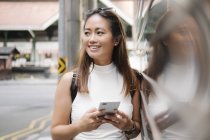 Jovem asiático atraente mulher usando smartphone na cidade rua — Fotografia de Stock