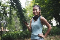 Молода азіатська спортивна жінка використовує смартфон у парку — стокове фото
