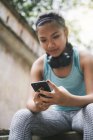Young asian sporty woman using smartphone — Stock Photo