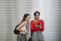 Young asian female friends together on city street on city street — Stock Photo