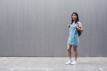 Jovem asiático faculdade estudante posando contra cinza parede — Fotografia de Stock