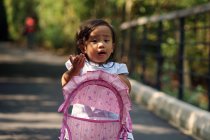 Cute little asian girl in park with baby carriage — Stock Photo