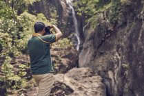 Vue arrière d'un jeune homme prenant des photos à la cascade de Klong Plu, Thaïlande — Photo de stock