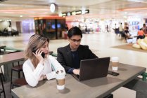 Exitoso negocio asiático pareja juntos trabajando con laptop en aeropuerto - foto de stock