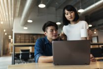 Due giovani asiatici al lavoro con laptop in ufficio moderno — Foto stock