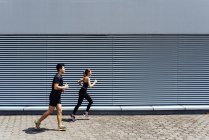 Sportliches junges Paar läuft gemeinsam auf Stadtstraße — Stockfoto
