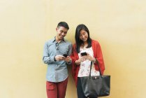 Chino asiático que pasa el tiempo juntos en Chinatown mirando en teléfonos inteligentes - foto de stock