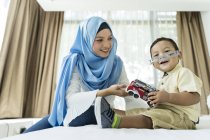 Молода азіатська мусульманська мати і дитина розважаються вдома з іграшками — стокове фото