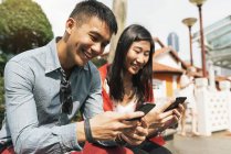 Jovem feliz asiático casal usando smartphones em Chinatown — Fotografia de Stock
