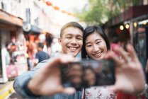 Joven feliz asiático pareja tomando selfie en chinatown - foto de stock
