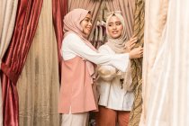 Dos chicas musulmanas en una tienda comprando cortinas - foto de stock
