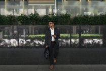 Homem de negócios indiano bonito usando smartphone no centro de negócios — Fotografia de Stock