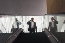 Schöner indischer Geschäftsmann spricht auf der Rolltreppe mit dem Smartphone — Stockfoto
