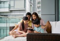 Счастливая молодая азиатская семья вместе с помощью цифрового планшета дома — стоковое фото