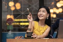 Feliz asiático jovem mulher comer no café — Fotografia de Stock