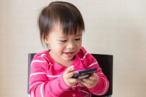 Joven poco asiático niño chica usando smartphone - foto de stock