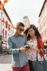 Joven feliz asiático pareja usando smartphone en chinatown - foto de stock