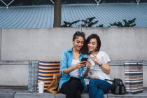Дві молода красива азіатська жінка використовує смартфон на покупках разом — стокове фото