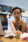 Jeune attrayant asiatique femme écriture notes dans café — Photo de stock