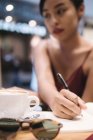 Jeune attrayant asiatique femme écriture notes dans café — Photo de stock